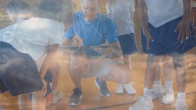 Coach kneeling on court tapping stylus summoning animated data overlays for training children peer. Educator, youth, mentorship, digital, sports, education, teamwork - Powered by Shutterstock - Get 15% off with code: PIKWIZARD15