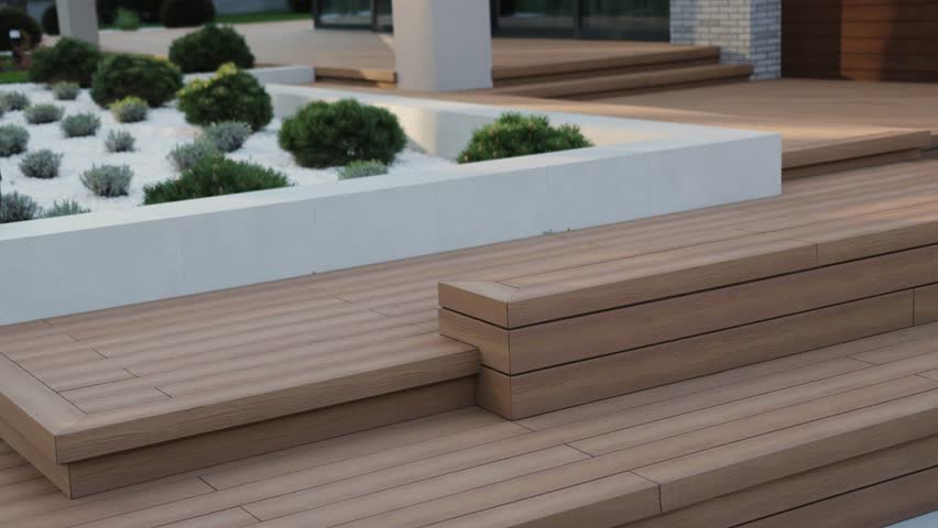 Outdoor wooden terrace showcasing modern aesthetics and elegance. Wooden terrace next to a modern house. Modern residential design with landscaped garden, large windows and elegant wooden terrace.