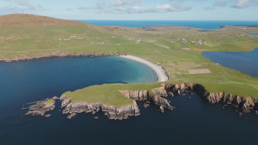 An aerial shot of beautiful Scousburgh Sands, in Scousburgh Shetland on a warm, calm summers day in Northern Scotland.