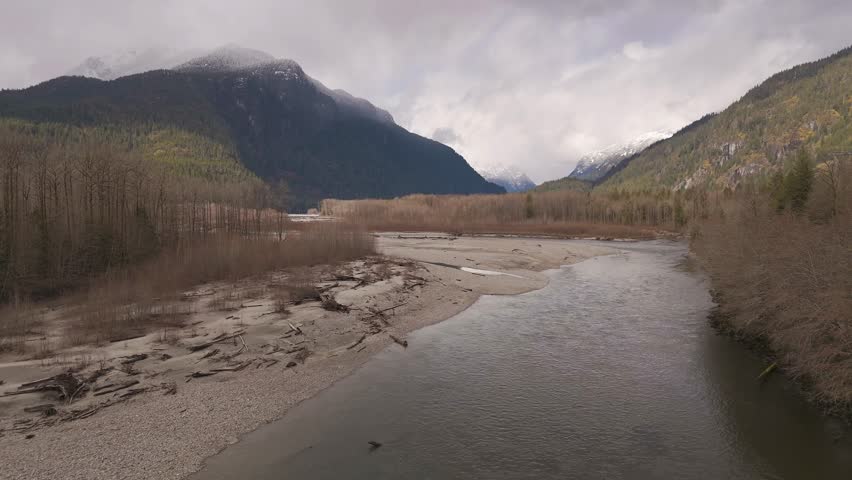 Scenic river flowing through mountains in British Columbia, Canada during cloudy day.