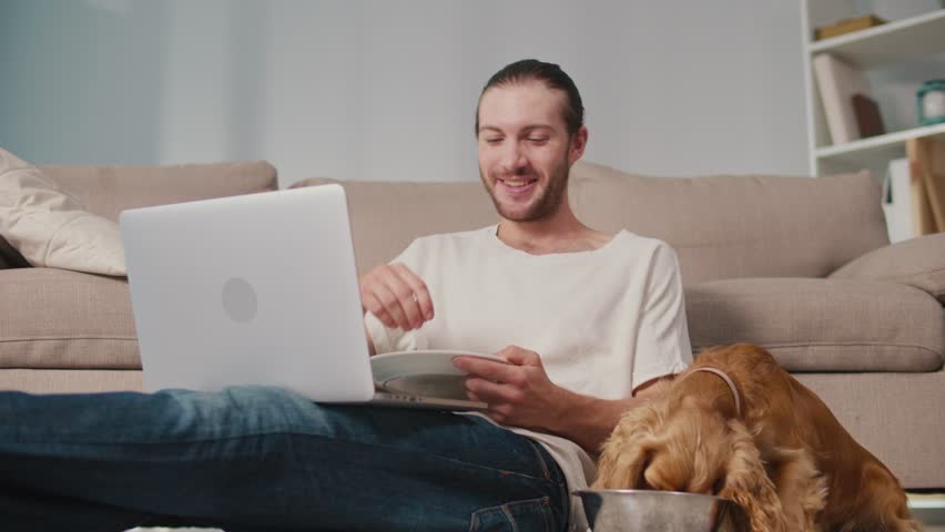 Healthy Routine, Pet Human Nutrition, Digital Balance. Man Works and Eats at Desk While His Dog Enjoys Its Own Food Nearby. Calm, Synchronized Wellness and Everyday Focus