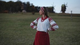 A young woman in an embroidered folk blouse and red beads stands with crossed arms in a grassy field. Her calm and confident expression highlights the grace of traditional heritage. - Powered by Shutterstock - Get 15% off with code: PIKWIZARD15
