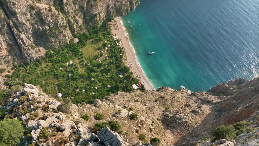 Aerial view of butterfly valley in fethiye, turkey, revealing turquoise waters nestled between dramatic cliffs and pristine beach under summer sunlight