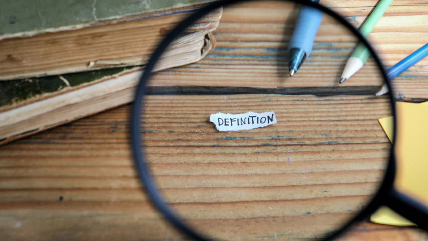 DEFINITION. Magnifying glass on a wooden textured office table. 4K Video