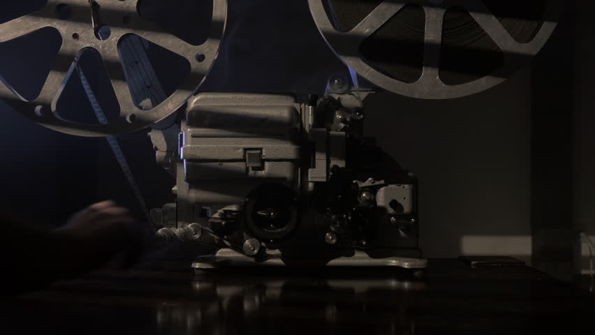 Projectionist turns on old movie projector to show film.