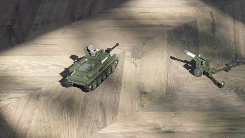 A detailed view of toy tanks and artillery resting on a wooden surface, showcasing intricate designs.