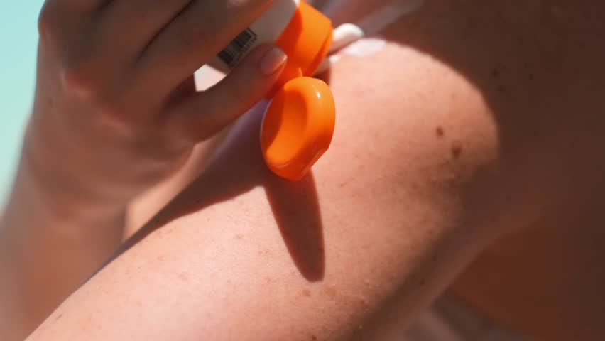 Woman applying sunscreen cream lotion on white tropical beach, summer skincare, sun protection, traveling, skin care, sunburn treatment and health