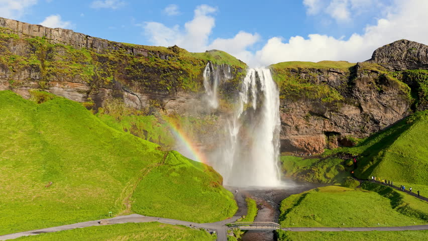 Seljalandsfoss Waterfall in Iceland, highlighted by a beautiful rainbow