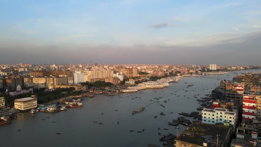 Buriganga River in Dhaka, Bangladesh. Traditional cargo boats, passenger ferries, and various river vessels navigate the waterway, showcasing the vital role of river transport in Dhaka