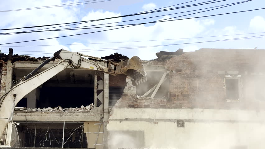 Excavator tears down a war-damaged building in Ukraine, clearing ruins after conflict. Scene reflects destruction, cleanup, and the beginning of postwar recovery and reconstruction efforts.