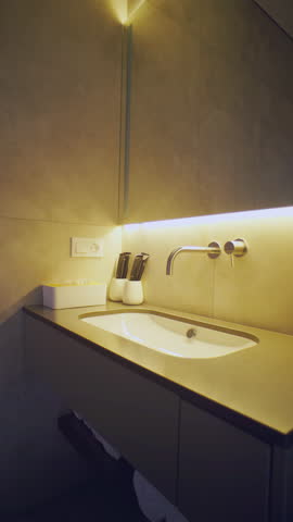 Travertine vanity and vessel sink washed by hidden LED strip. Steam-ready ambience fits wellness, architectural or renovation storytelling.