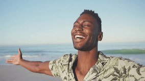 Marketing ad showing man spreading arms on beach as American flag overlay fading in evoking pride. Patriotism, celebration, outdoor, leisure, relaxation, coastal, vibrant - Powered by Shutterstock - Get 15% off with code: PIKWIZARD15