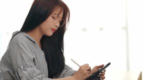 Young woman immersed in artistic work while using a digital tablet in a well-lit office. She expresses creativity and focus, embodying a modern creative lifestyle. - Powered by Shutterstock - Get 15% off with code: PIKWIZARD15