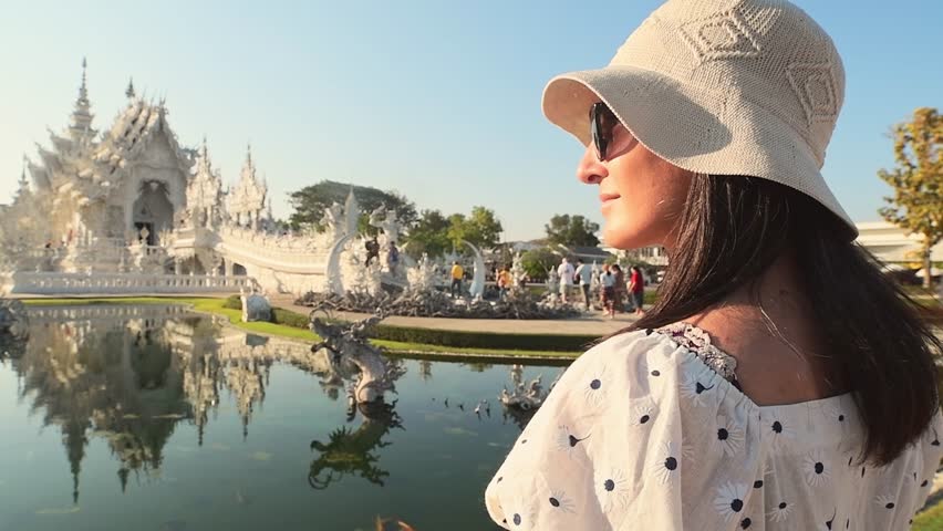 Chiang Rai, Thailand - 2024: Tourist woman traveler wear white dress sightseeing at Wat Rong Khun White Temple Chiang Rai Thailand.Modern Buddhist art temple. Travel blogger pose in tourist attraction