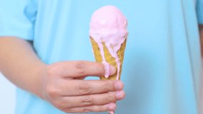 Child holding melting pink strawberry ice cream cone, sticky drips cascading down waffle cone against bright blue background - Powered by Shutterstock - Get 15% off with code: PIKWIZARD15