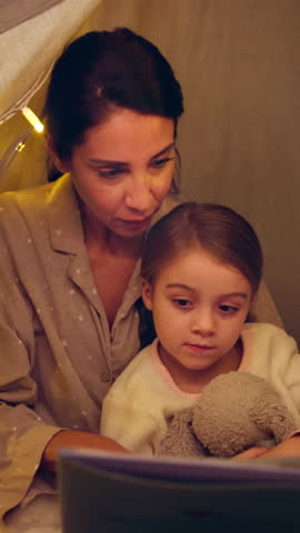 Mother, kid and reading book in tent at night for storytelling, bedtime story and learning. Woman, talking and child with novel for fairytale, language development and literature education at house