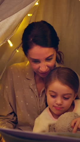 Mother, child and reading book in tent at night for storytelling, bedtime story and learning. Woman, talking and kid with novel for fairytale, language development and literature education at house