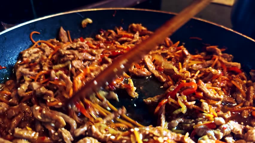 Thai cuisine stir-fried meat with carrots and bell peppers in a hot pan. Juicy, savory, and richly sauced, the dish sizzles with flavor, showcasing delicious Asian-style home cooking. Stir fried dish