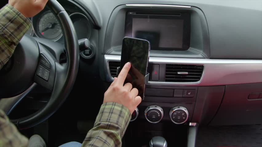 Close-up of African American female driver sitting in car, searching for travel route on smartphone using modern GPS navigation app while driving vehicle on road trip.