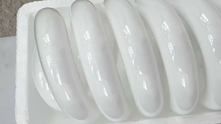 Large spiral compact fluorescent light bulb (CFL) in protective white foam packaging. Energy-saving daylight lamp with E27 screw base on light wooden background, top view