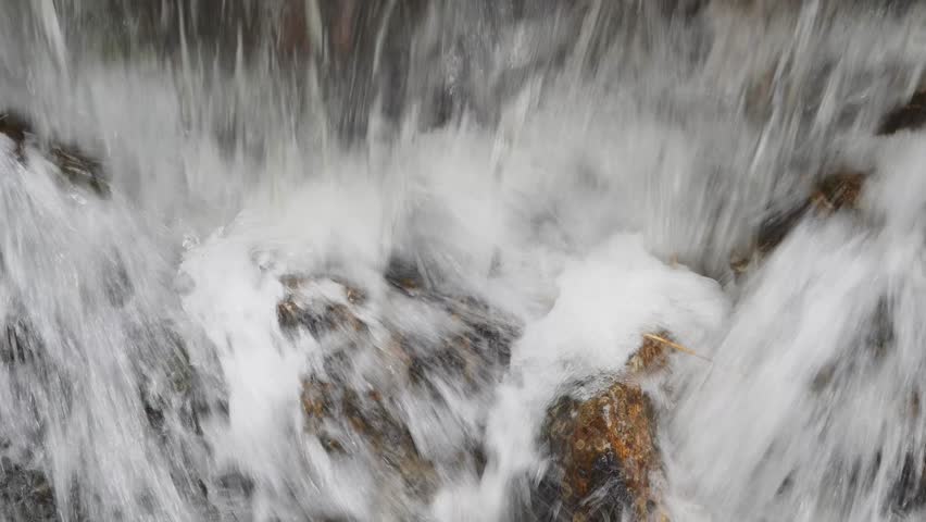 Closeup of powerful natural waterfall with splashing water and rocks. Rapid waterfall cascading over rocks with fresh clear water splash
