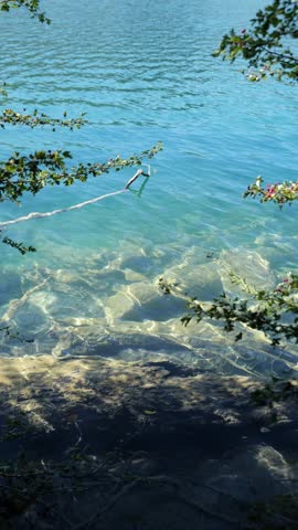 A peaceful waterfall flowing into a lake. A peaceful lake reflecting the summer sky. Summer nature. A tranquil lake surrounded by mountains in Croatia. A peaceful summer view of Plitvice Lakes.
