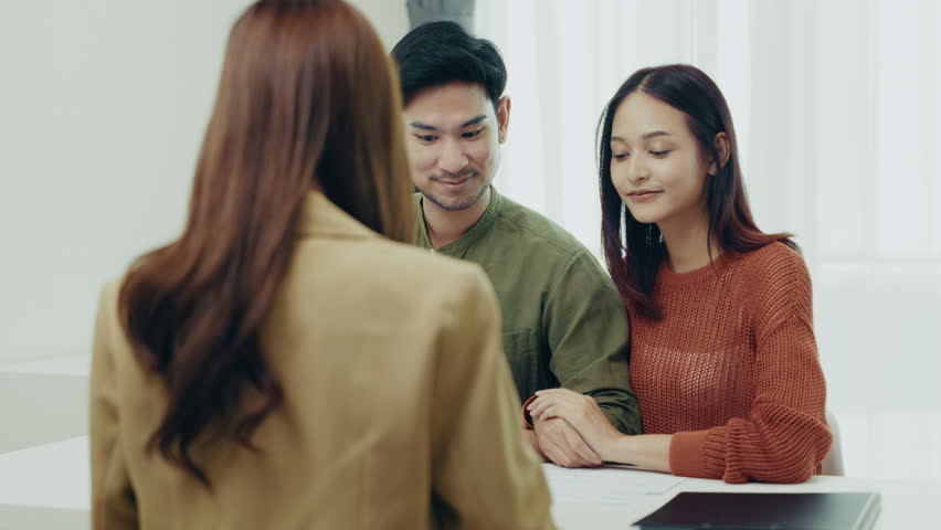Smiling Asian couple meeting with a financial advisor for consultation. Concept of finance planning, investment discussion, and relationship goals.