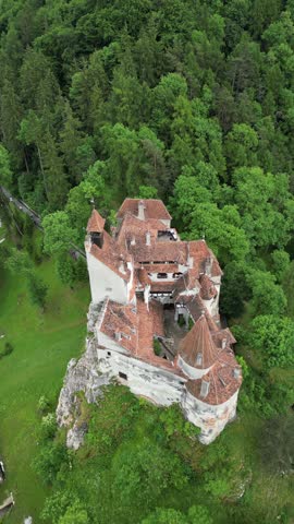 Aerial view of the picturesque Bran Castle surrounded by lush green forest and trees, Bran, Brasov, Romania.