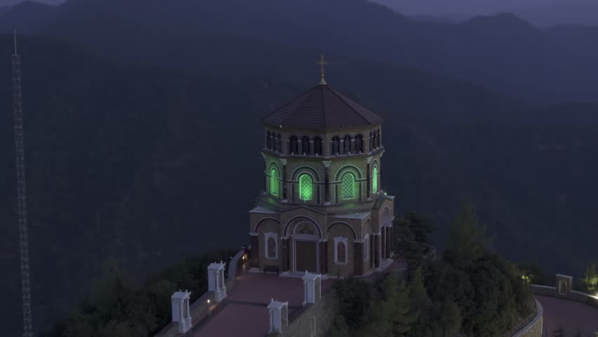 Aerial view of throni church illuminated at night surrounded by mountains and forest, Tsakistra, Nicosia, Cyprus.