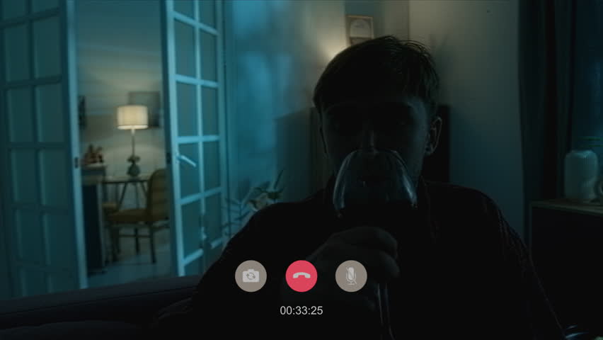 Handheld shot of relaxed man drinking wine video calling when doors bursting open then books falling off table scaring boy with paranormal phenomenon of poltergeist in empty house at night