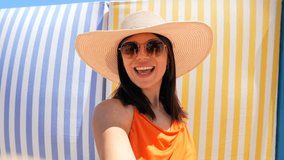Female social media influencer recording lifestyle content, smiling while wearing orange top and sunhat during beach vacation, creating engaging online material - Powered by Shutterstock - Get 15% off with code: PIKWIZARD15