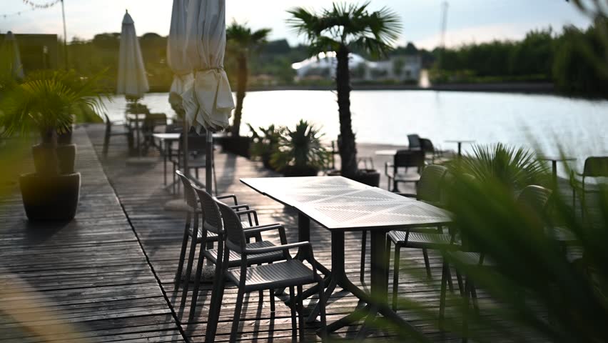 Peaceful Waterfront Restaurant on a Wooden Deck with Palm Trees at Golden Hour.