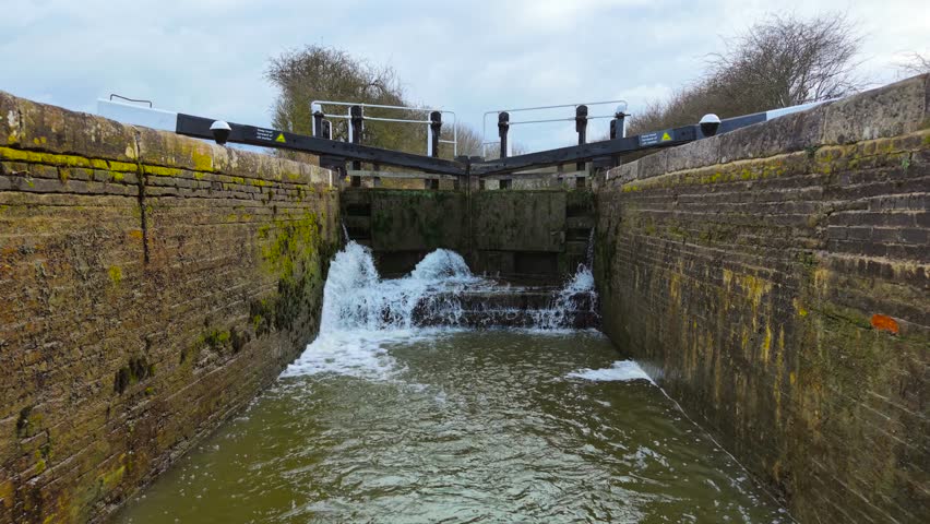 Lock gate releasing surging water into canal. Sluice system controlling fluid movement. Hydraulic mechanism adjusting navigation flow. Waterway lock managing level transition