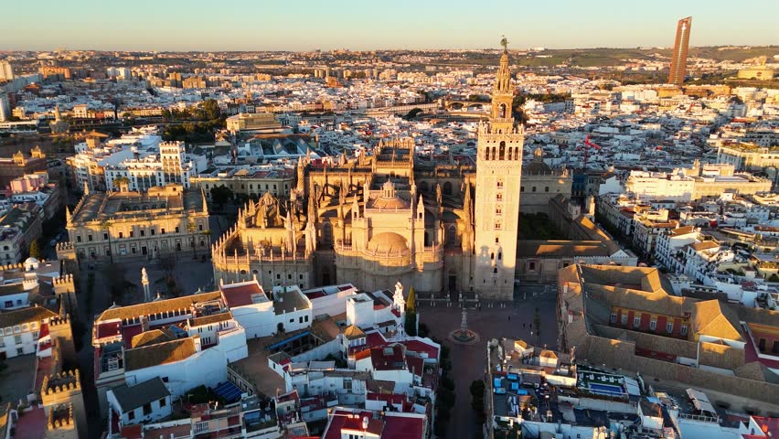 Aerial view of Seville Cathedral and La Giralda in Seville, Spain, showcasing historic architecture and urban landscape during sunset.