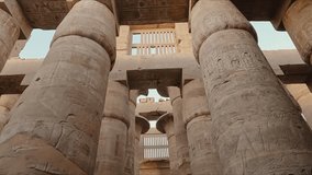 Majestic view of the towering stone columns inside the Karnak Temple complex in Luxor, Egypt. The pillars are adorned with intricate hieroglyphic carvings and symbols from ancient Egyptian history. - Powered by Shutterstock - Get 15% off with code: PIKWIZARD15