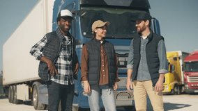 Three proud logistics workers looking directly at camera, standing confidently in front of parked blue truck. Wearing casual outdoor vests and caps, posing as a team under clear daylight. - Powered by Shutterstock - Get 15% off with code: PIKWIZARD15