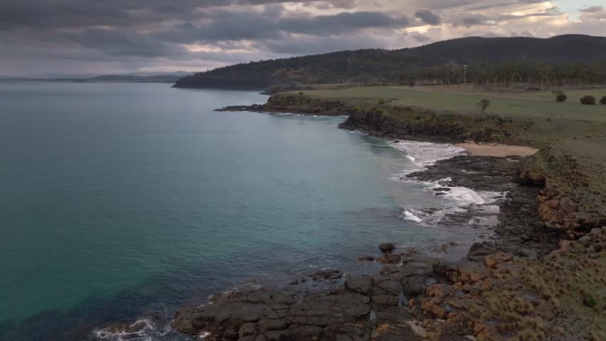 Aerial footage of Kelvedon Beach, Tasmania at sunrise. Captured after a night storm, the video shows moody skies, soft light, and serene coastal beauty in 4K.