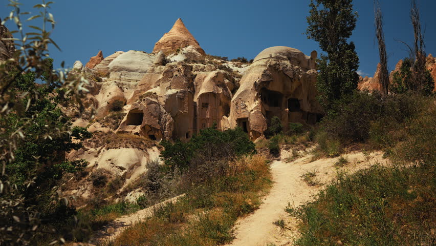 Traditional building with windows carved into volcanic rock in Cappadocia, Turkey. Unique stone architecture in a scenic rocky landscape.