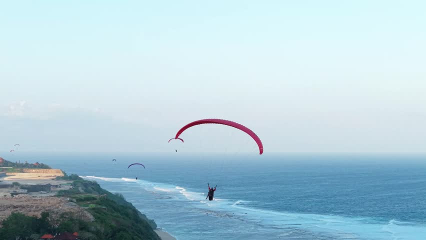 4K aerial shot following a paraglider flying over the ocean. Stunning summer scenery, perfect for travel promos, adventure content, sports commercials, and lifestyle videos.