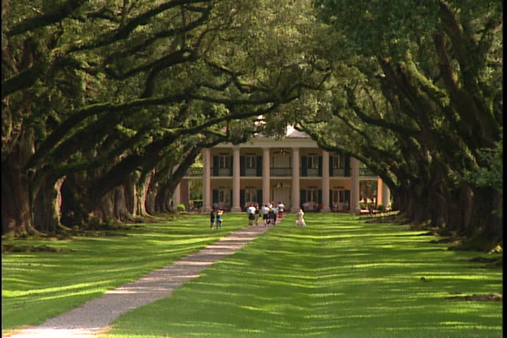 CONVENT, LOUISIANA - SEPTEMBER 4, 1999: Oak Alley Plantation House seen at end of path covered by a canopy of oak trees.