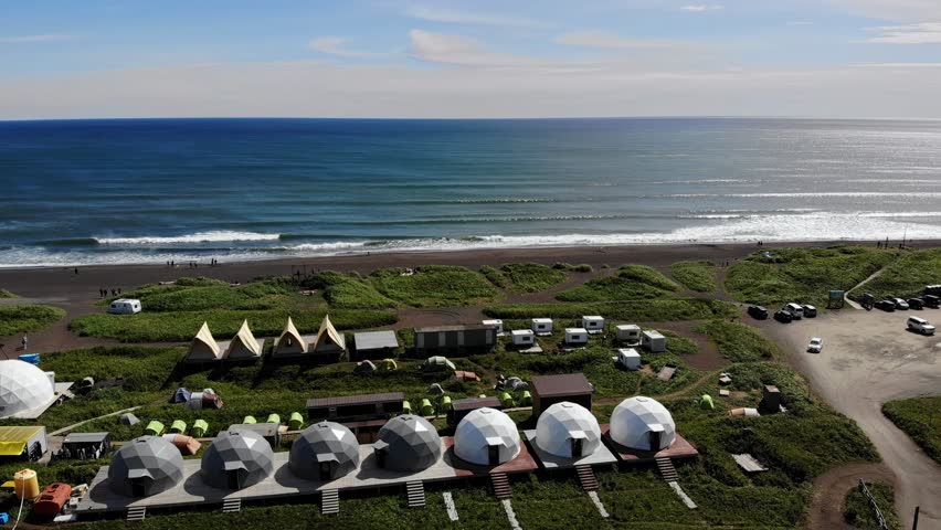 White glamping on Landscape of Khalaktyrsky beach with black volcanic sand coast of North Pacific Ocean Kamchatka Russia, aerial top view.