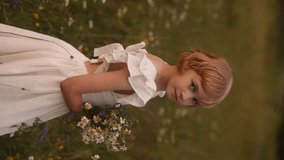 Young blonde girl in white dress standing in flower field holding bouquet of flowers. Rural scene, peaceful and serene, girl looking down. - Powered by Shutterstock - Get 15% off with code: PIKWIZARD15