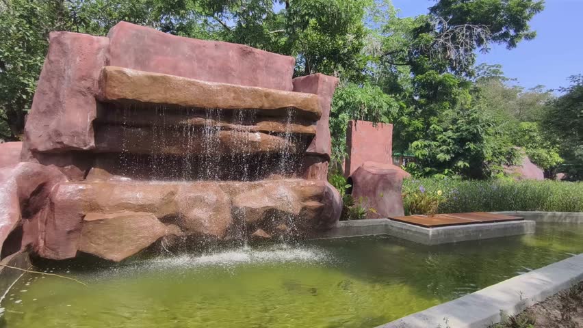 Tranquil Outdoor Landscape Serene Waterfall Cascades Over Natural Stone Formations Amidst Lush Greenery and Peaceful Pond