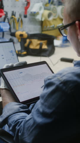 Worker Monitoring Real-Time Stocks, Exchange Market Charts Using Tablet Computer and Laptop. Man Making Investments During Working Day in Workshop, Combining Job with Online Trading. Vertical Shot.