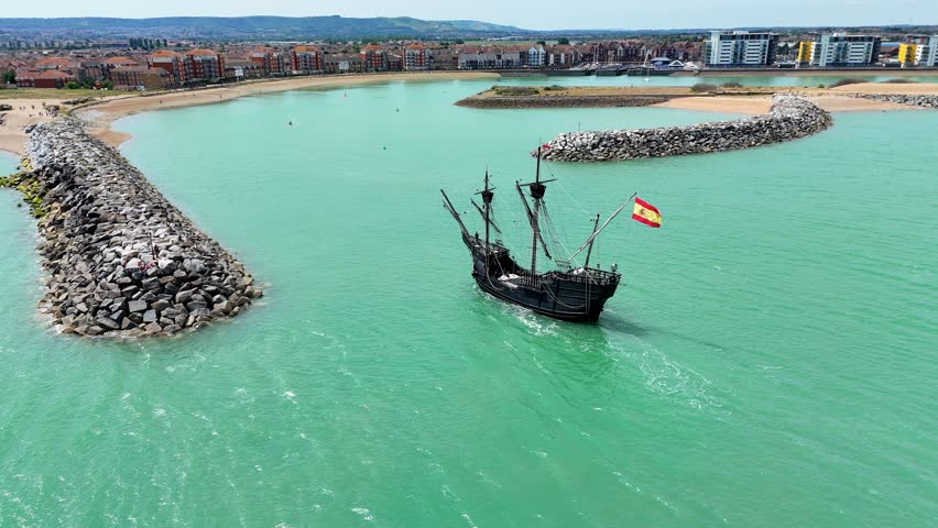 Aerial view of the majestic Nao Victoria ship gliding into Sovereign Harbour, Eastbourne. Historic charm meets coastal beauty in this cinematic maritime moment.