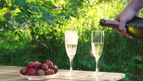 Hand pours champagne into flutes on sun-drenched wooden table, next to bowl of ripe strawberries against vibrant green garden backdrop. Perfect for themes of summer celebrations and outdoor indulgence - Powered by Shutterstock - Get 15% off with code: PIKWIZARD15