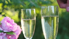 Close-up of sparkling wine being poured into glass with another glass next to it, against blurred background of bouquet of roses and green garden. Perfect for summer and romantic themes - Powered by Shutterstock - Get 15% off with code: PIKWIZARD15