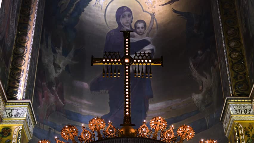 An illuminated Orthodox cross is framed against the stunning ceiling fresco of the Virgin and Child inside Kyiv