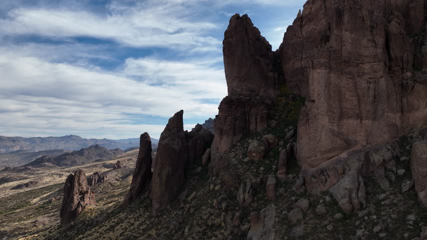 Aerial view of majestic Superstition Mountains with rugged rock formations under a serene sky, Apache Junction, Arizona, United States.