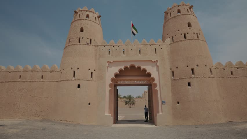 A slow motion footage of the flag of the United Arab Emirates waving over the entrance of Al Jahili Fort on a sunny day in Al Ain, Abu Dhabi, the UAE